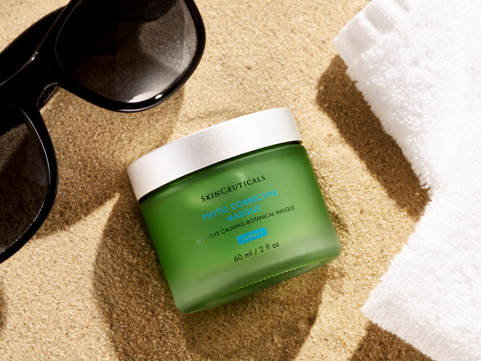 Phyto Corrective Masque by SkinCeuticals, jar sitting on sand next to sunglasses and a towel.