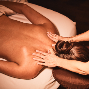 Woman lying face down on a massage table, receiving a massage spa package from a licensed massage therapist.