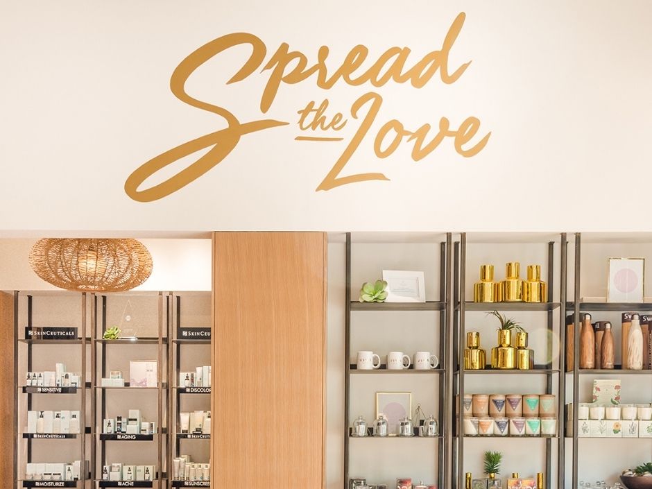 "Spread the Love" mural in the retail area of Viva Day Spa Domian Northside, over the SkinCeuticals product shelves.