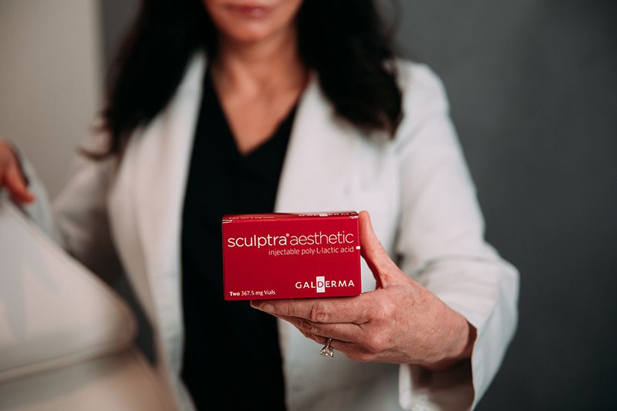 Aesthetic nurse practitioner at Viva Day Spa + Med Spa holding a box Sculptra filler, a collagen replacement solution