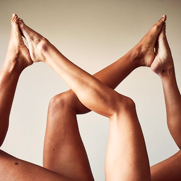 Legs of two women with dark and light skin tones in air together after laser hair removal sessions.