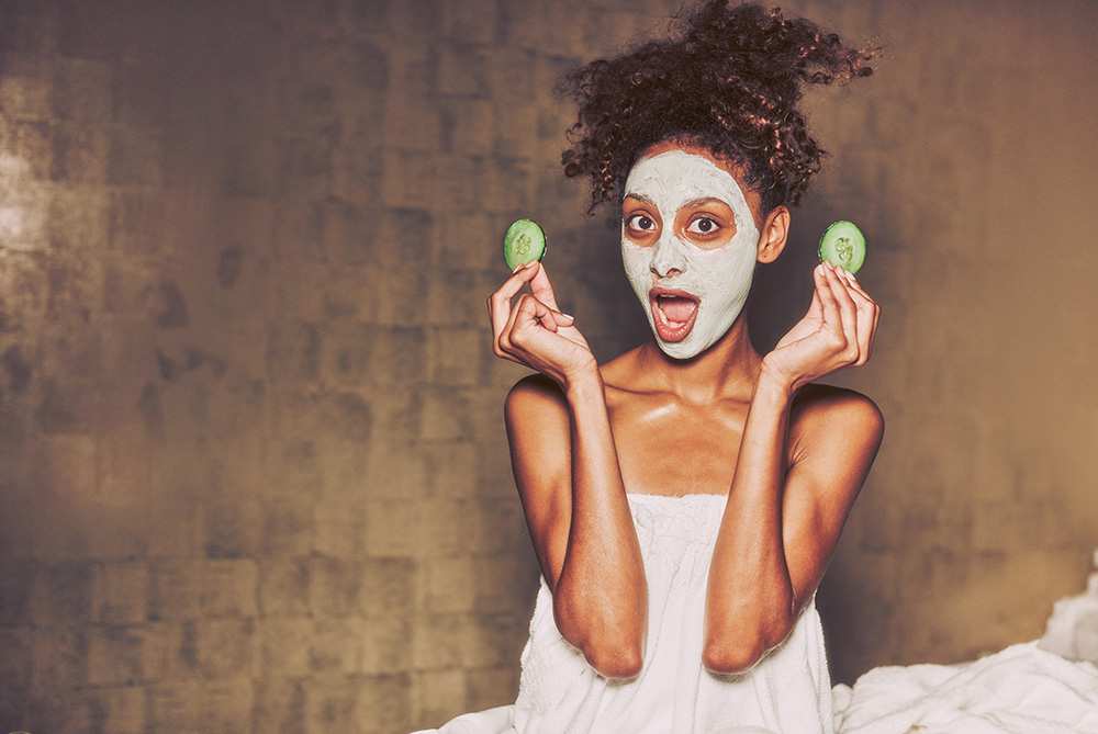 Woman wearing a masque pulling cucumbers off of her eyes during a facial at Viva Day Spa + Med Spa in Austin, Texas.