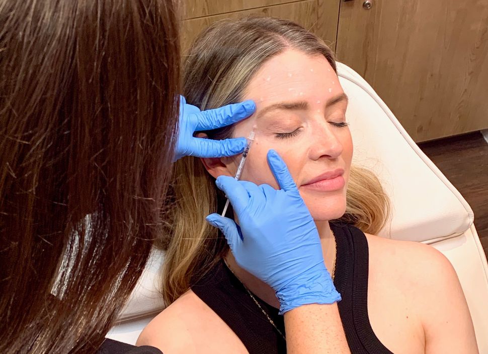 Woman receiving Botox injections in her forehead and crow's feet.