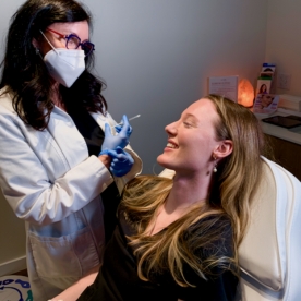 A licensed injector prepares to administer a cosmetic injectable treatment to a smiling guest at Viva Day Spa + Med Spa.